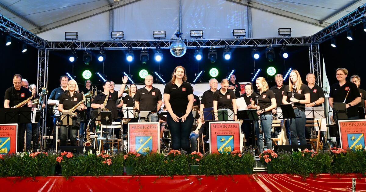Nach 56 Jahren: Musikzug Kirchtimke feiert in Zeven eine Premiere Männer und Frauen in schwarzen Poloshirts stehen auf einer beleuchteten Bühne in einem Festzelt