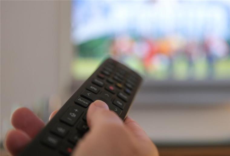 Eine Hand bedient eine Fernbedienung für ein TV-Gerät.