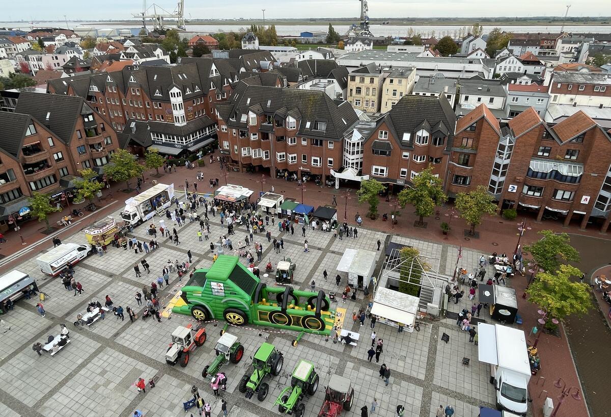 Der Ochsenmarkt auf dem Nordenhamer Marktplatz aus der Vogelperspektive. In der Mitte steht eine große Hüpfburg in Form eines Trekkers. Drumherum stehen echte Trekker und Marktbuden.