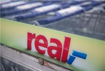 Das "Real"-Logo ist an einem Unterstand für Einkaufswagen des Real Supermarktes zu sehen. 