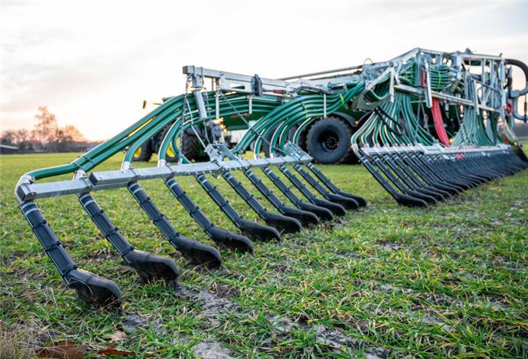 Ein Landwirt bringt mit seinem Gespann Gülle auf einem Feld aus
