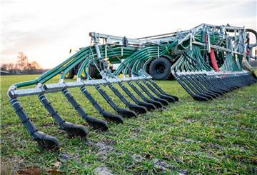 Ein Landwirt bringt mit seinem Gespann Gülle auf einem Feld aus
