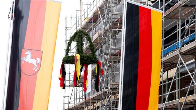 Der Richtkranz ist beim Richtfest für das Museum Friedland hinter Flaggen zu sehen.