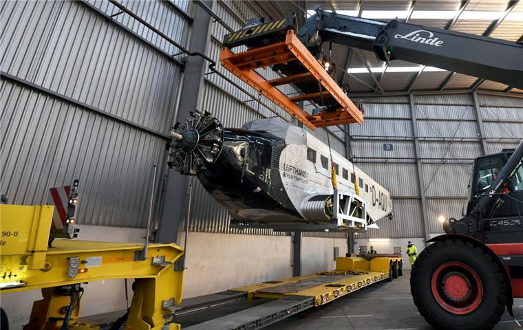 Der Rumpf einer Junkers 52 (Ju 52) der Lufthansa wird in einer Halle am Hafen in Bremen von einem Kran gehoben um sie an ihren Platz zu setzen. 