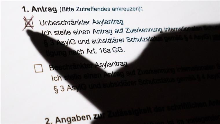 Der Schatten eines Kugelschreibers zeichnet sich auf einem Asylerstantrag ab.
