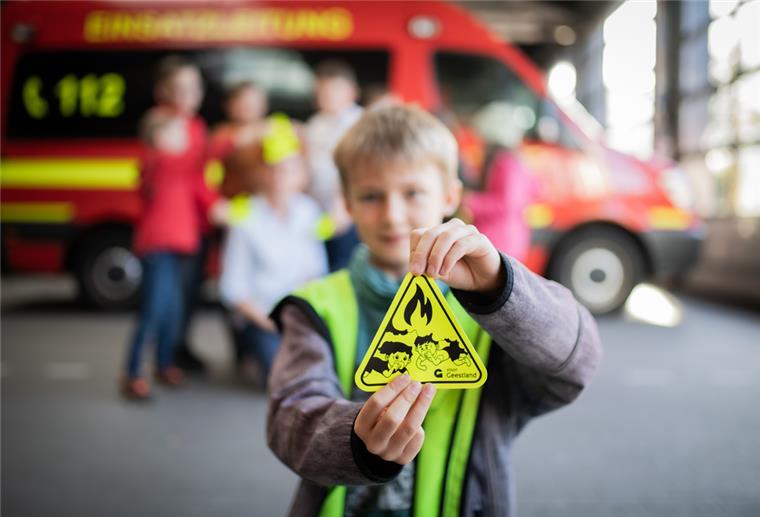Ein Junge hält den Aufkleber "Kinderfinder" in die Kamera.
