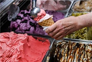Eine Kugel Erdbeereis wird in einer Eisdiele auf eine weitere Kugel in einem Waffelhörnchen gesetzt. Im Sommer 2025 kommen auf uns höhere Eispreise zu. 