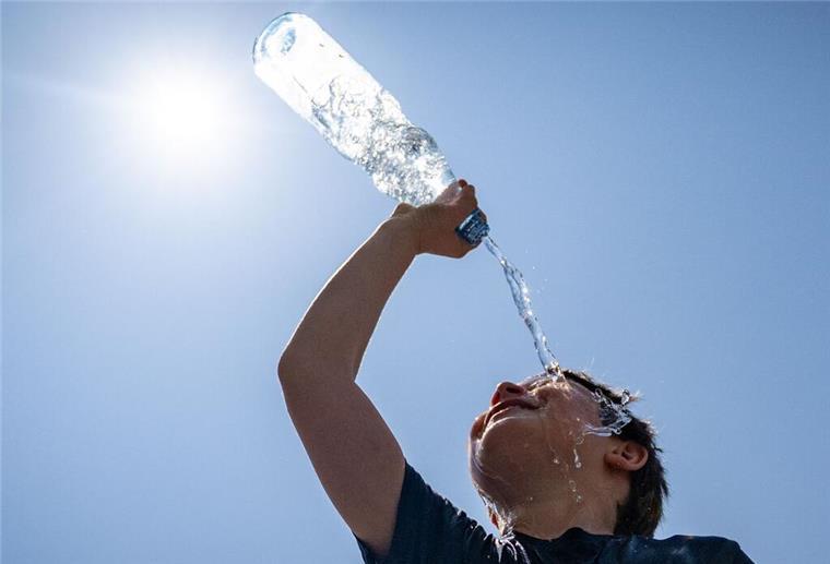Ein Junge kühlt sich mit einer Flasche Wasser ab.