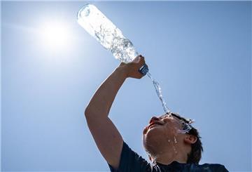 Ein Junge kühlt sich mit einer Flasche Wasser ab.