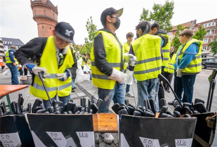 Kinder mit Warnwesten sammeln Müll auf dem Konrad-Adenauer-Platz in Bremerhaven.