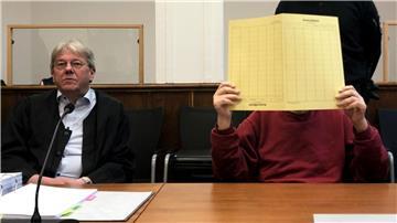 Mutter mit Kissen erstickt: Sohn zu Haftstrafe verurteilt Der wegen Mordes vor dem Landgericht Angeklagte hält sich eine gelbe Pappmappe vor das Gesicht.