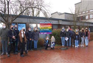 Der Wegweiser mit seinen Botschaften auf den Latten in Regenfarben ist erneuert worden und steht wieder am Eingang zum Gymnasium. Darüber freuen sich die SV-Mitglieder und ihre Unterstützer.