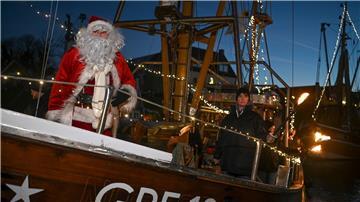 Der Weihnachstsmann kommt mit einem Fischkutter im Hafen an.