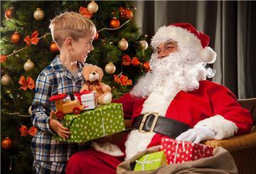 Ein Weihnachtsmann mit einem kleinen Jungen unterm Tannenbaum