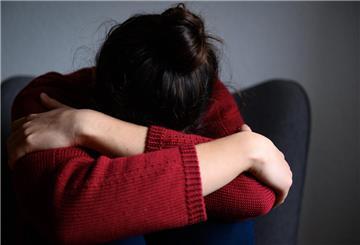  Eine Frau sitzt mit dem Kopf in den Armen versunken auf einem Stuhl. 