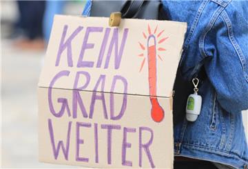 Ein Aktivist der Klimaschutzbewegung Fridays for Future trägt bei einer Demonstration auf dem Domplatz für eine bessere Klimapolitik ein Plakat mit dem Motto "Kein Grad weiter".