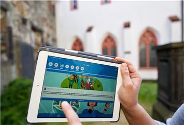 Ein Mann zeigt auf einem Tablet die App "Dorffunk".