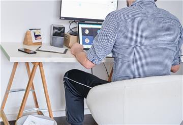 Ein Mann nimmt an einem Online-Meeting teil, während er oben herum ein Hemd trägt und unten herum eine Jogginghose. 