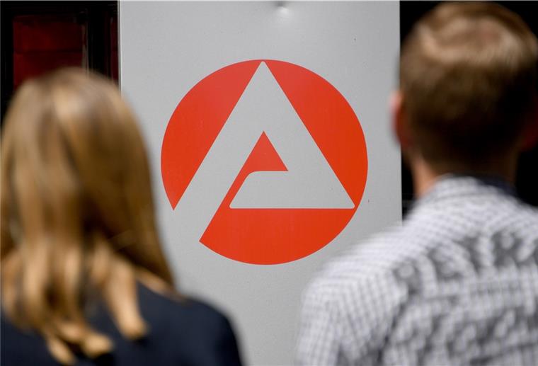 Zwei Personen stehen vor dem Logo der Agentur für Arbeit.