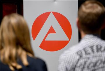 Zwei Personen stehen vor dem Logo der Agentur für Arbeit.