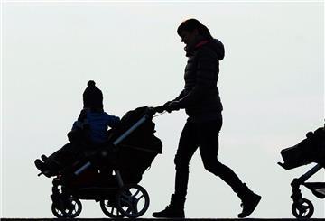 Zwei Mütter schieben ihre Kinderwagen eine Landstraße entlang.