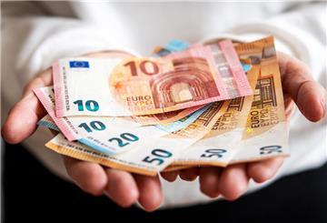 Eine Frau hält mehrere Geldscheine in ihren Händen und zeigt sie dem Betrachter. Bald sollen sich die Deutschen über Klimageld freuen können, doch es gibt einen Haken.