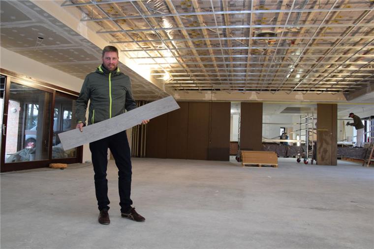 Die Bauarbeiten im „Haus im Löh“ in Rockstedt schreiten voran. Der stellvertretende Gemeindebürgermeister Volker Borchers zeigt den Design-Belag in Holz-Optik, der bald den Fußboden zieren soll. Zudem wird der Saal mit einer Akustikdecke ausgestattet.