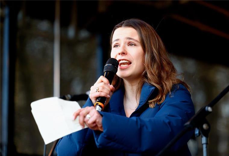 Luisa Neubauer, Klimaaktivistin, steht auf einer Bühne und spricht in ein Mikrofon. 