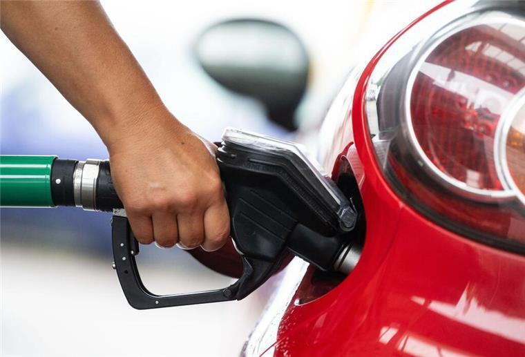 Ein Mann hält an einer Tankstelle an einer Zapfsäule eine Zapfpistole in der Hand und betankt ein Auto. Die beste Zeit zum Tanken zu erwischen, wird immer schwieriger.