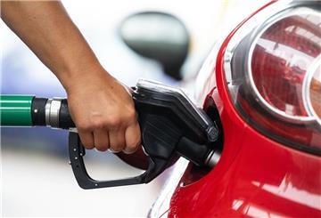 Ein Mann hält an einer Tankstelle an einer Zapfsäule eine Zapfpistole in der Hand und betankt ein Auto. Die beste Zeit zum Tanken zu erwischen, wird immer schwieriger.