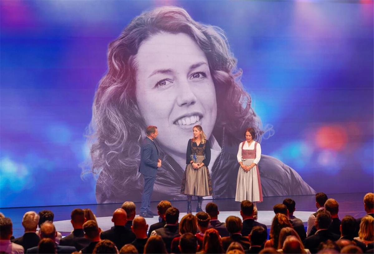 „Das Leben ist zu kurz“ – Biathletinnen würdigen Dahlmeier Die Biathletinnen Franziska Preuß und Magdalena Neuner (hier mir Moderator Markus Othmer vor einem Bild von Laura Dahlmeier) haben bei der Verleihung des Bayerischen Sportpreises ihrer gestorbenen Kollegin Dahlmeier gedacht.