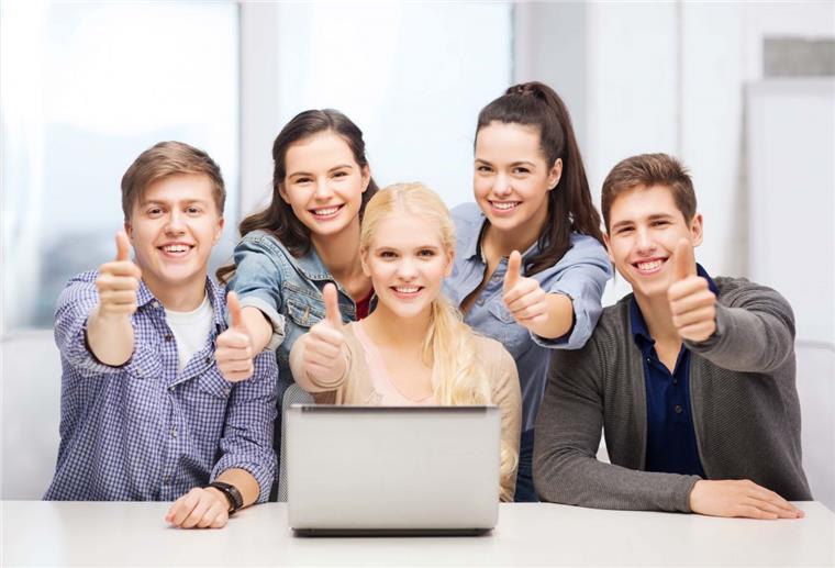 Lächelnde Schüler sitzen vor einem Laptop und halten die Daumen hoch. und machen den Bobrink Personality Test