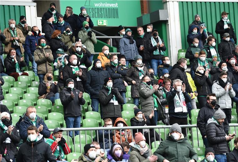 Werder Bremen Fans sitzen und stehen im Weserstadion und applaudieren.