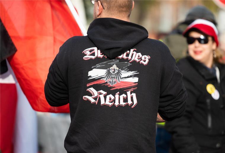 Ein Mann trägt einen Pullover mit dem Aufdruck „"Deutsches Reich" bei einer Demonstration von Reichsbürgern