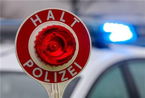ein Polizist hält eine Polizeikelle für eine Kontrolle