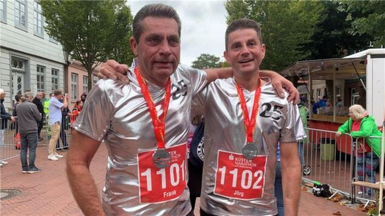 Zwei Läufer in silbernen Trikots Arm in Arm nach dem Zieleinlauf.