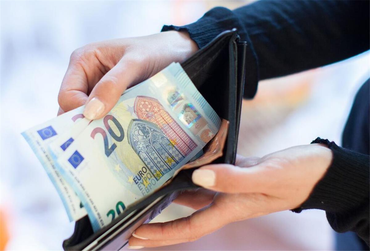 Eine Person hält Geldscheine in die Kamera. 