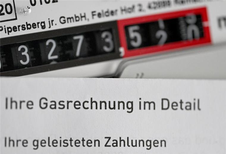 Eine Gasrechnung wird vor einen Gaszähler in einem privaten Haushalt gehalten