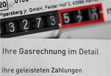 Eine Gasrechnung wird vor einen Gaszähler in einem privaten Haushalt gehalten