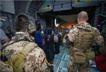Bundeswehrsoldaten und afghanische Flüchtlinge steigen in ein Militärflugzeug ein.