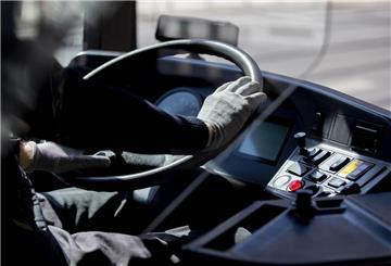 Ein Busfahrer hält das Lenkrad mit Handschuhen.
