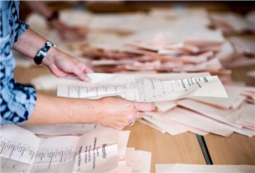 Eine Wahlhelferin sortiert in einer Grundschule, in der ein Wahllokal für die Kommunalwahl untergebracht ist, die Stimmzettel für die Auszählung.