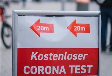 Passanten gehen in der Innenstadt an einem Schild vorbei, das auf eine Corona- Teststation und kostenlose Corona-Tests hinweist