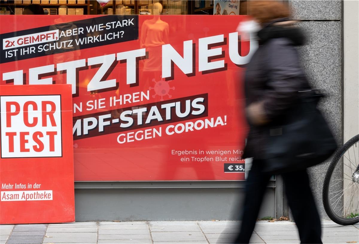 Ein Schild mit der Aufschrift "Jetzt Neu - Testen Sie ihren Impf-Status gegen Corona" ist in der Innenstadt von München im Schaufenster von einer Apotheke zu sehen