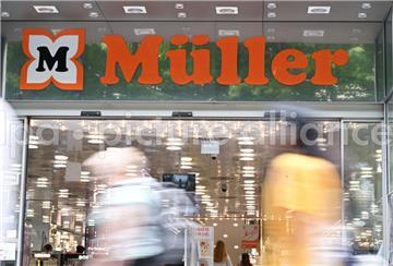 Das Logo der Drogeriemarktkette Müller ist am Eingang einer Filiale angebracht. Im Vordergrund laufen Passanten vorbei