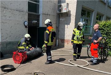 Einsatzkräfte der Feuerwehr stehen mit Schläuchen vor einem Gebäude