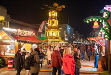 Menschen schlendern an Ständen eines Weihnachtsmarktes vorbei.