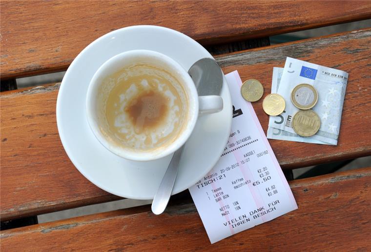 Eine Kaffeetasse mit einem Zahlungsbeleg steht auf einem Restauranttisch.
