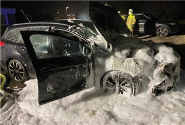 Ein ausgebranntes, schwarzes Auto voller Löschschaum.