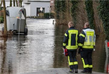 Feuerwehrleute stehen an einer überfluteten Wohnstraße